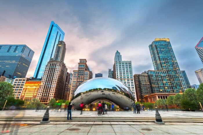 Chicago, IL, USA - May 12, 2018: Tourists visit Cloud Gate in Millennium Park in the evening. The sculpture was completed in 2006.